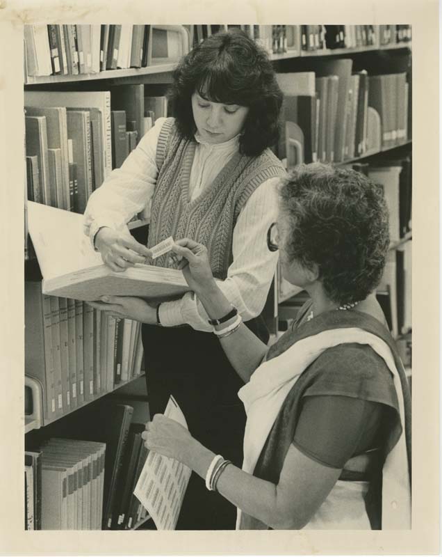 Two librarians at Oakland University applying barcodes to library books during the automation process in the 1980s.
