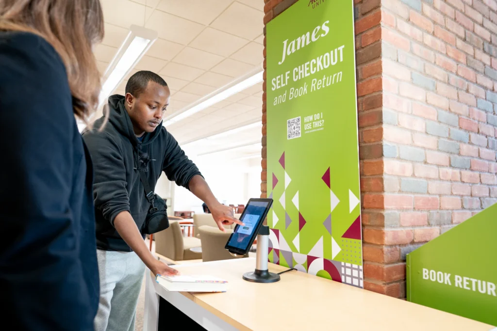 A student uses the James selfCheck station at Augsburg University’s Lindell Library, part of the library’s move toward full self-service.